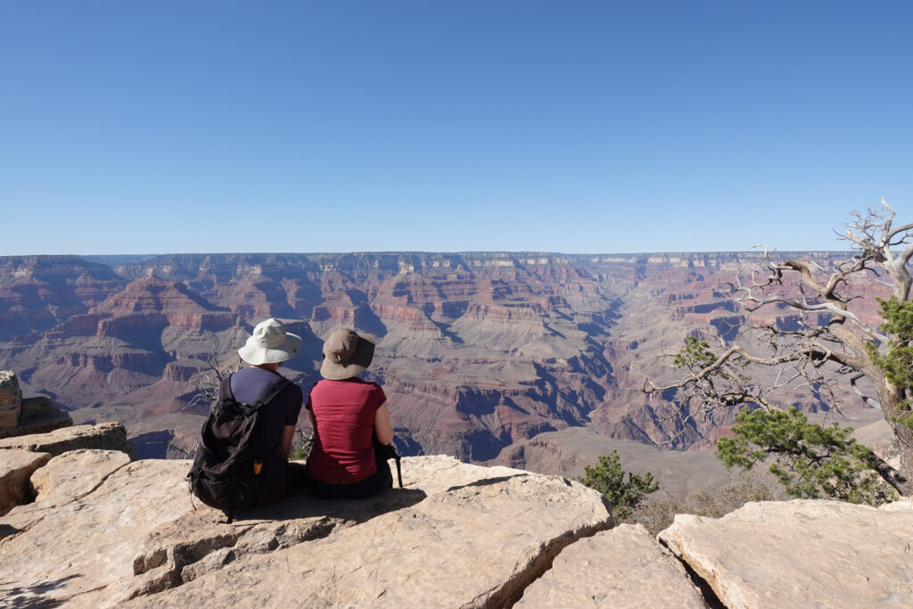 Two hikers sitting and looking over Grand Canyon