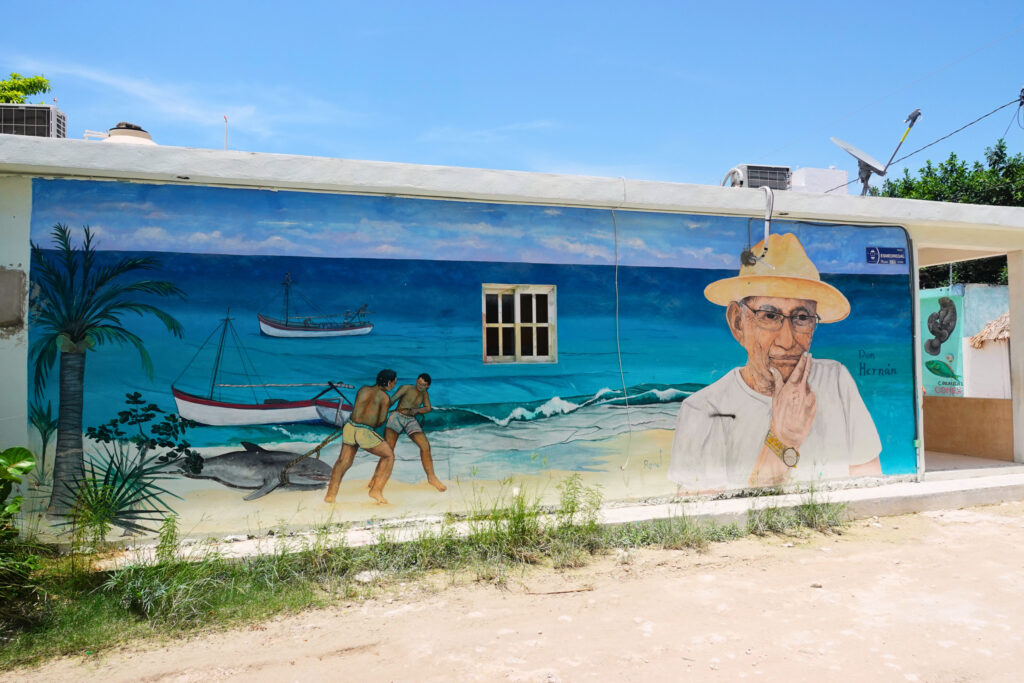 Wandmalerei auf Holbox, die eine Fischerszene am Strand darstellt.